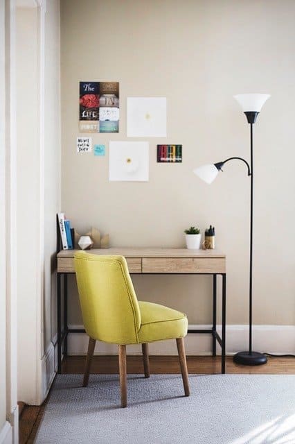 Petit bureau avec chaise verte et grande lampe à pied